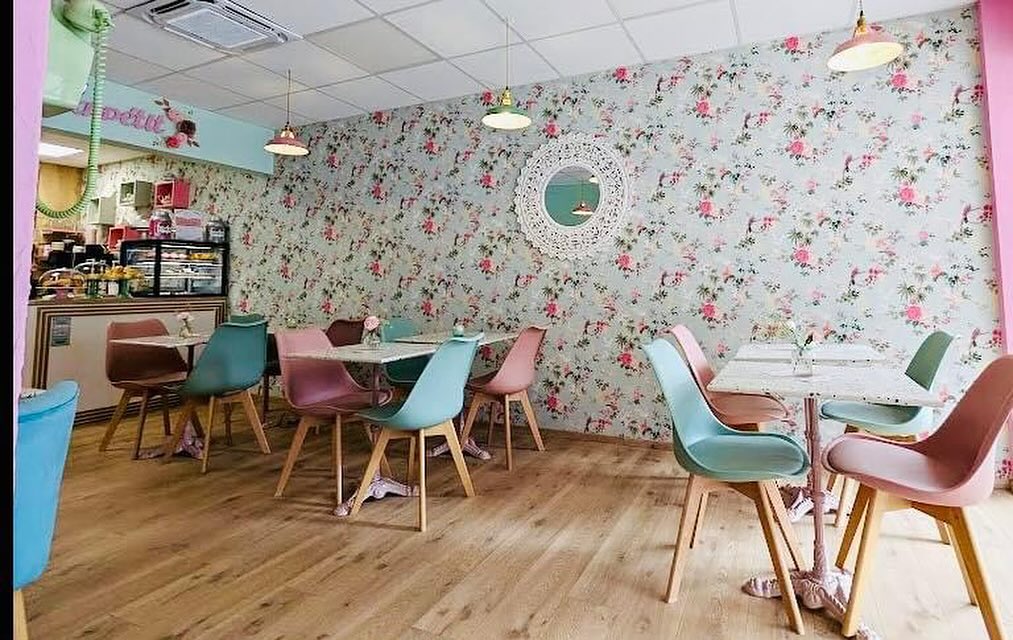 L’intérieur de Pink and Cosy : papier peint fleuri, fauteuils roses et verts