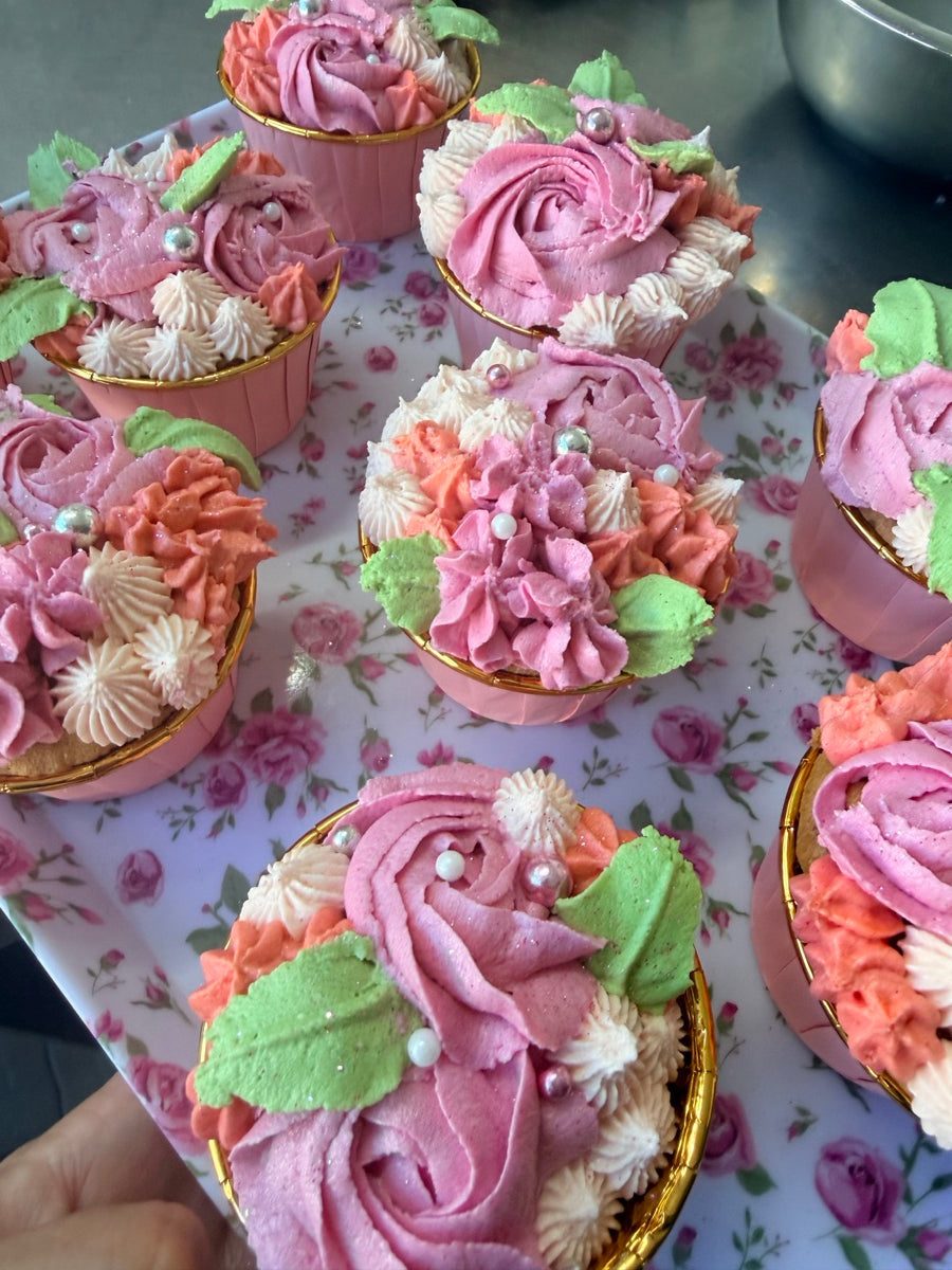 Rose, lilas, pêche et ivoire se rencontrent dans ce bouquet de cupcakes, rehaussé de feuilles vertes et de petites perles.