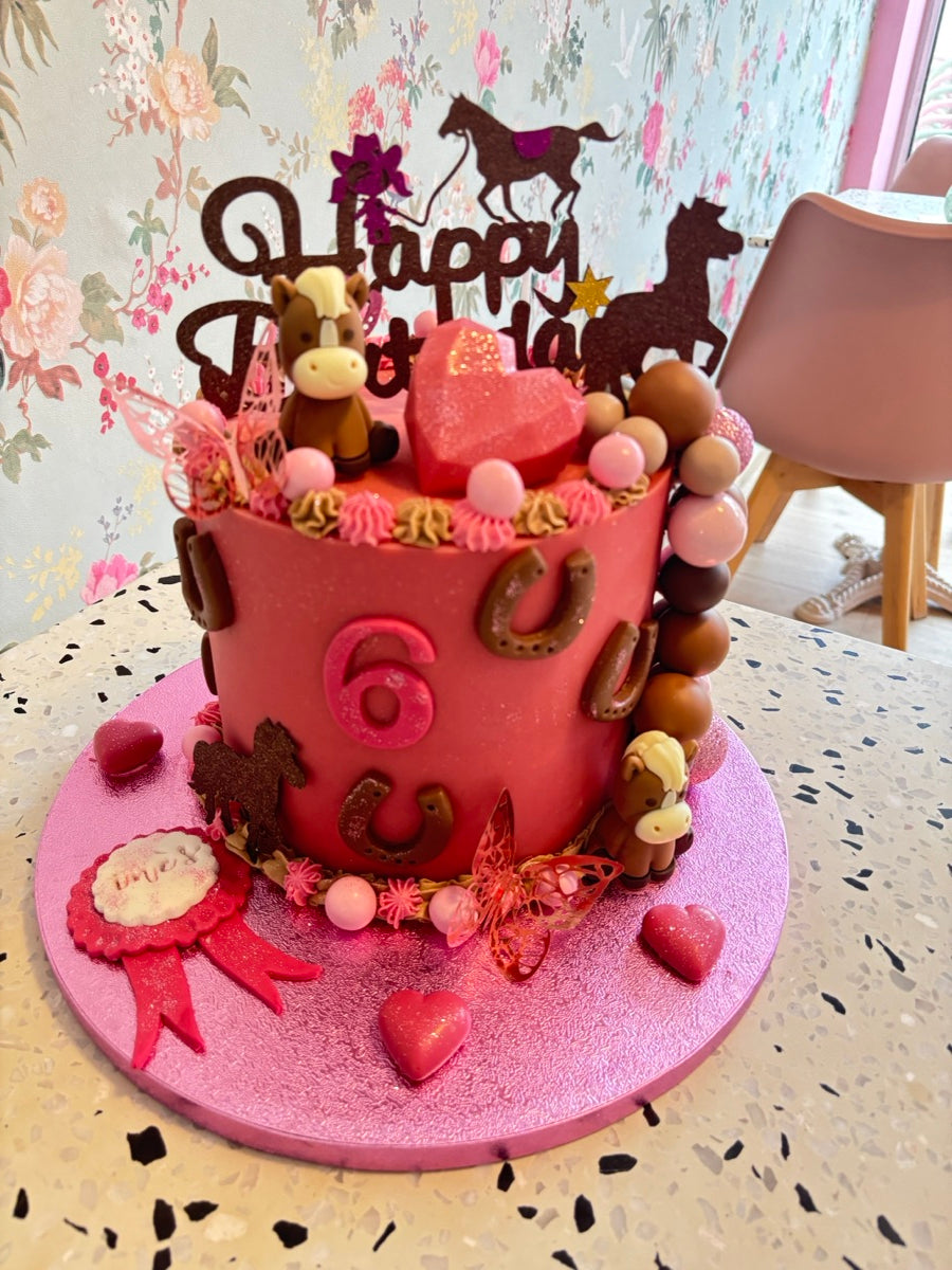 Un layer cake rose, des silhouettes de chevaux, des fers à cheval et de petits décors gourmands pour un anniversaire équestre.