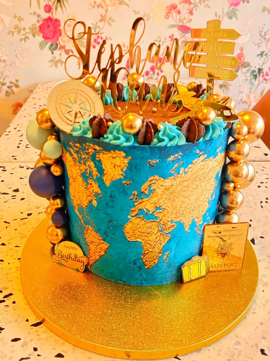 Un globe bleu et or transformé en layer cake, avec une carte du monde, une boussole et des petits détails de voyage.