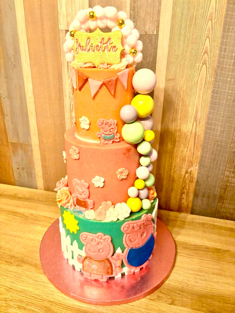 Une création haute et colorée, avec les personnages de Peppa Pig, des fanions, des petites fleurs et une cascade de boules pastel.