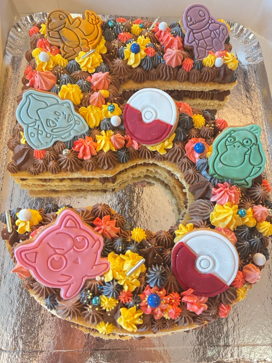 Un chiffre 5 aux pochages chocolat et aux touches multicolores, avec des personnages Pokémon et des Poké Balls.